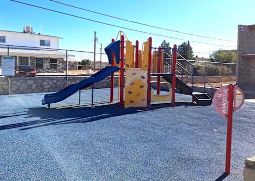 A playground with a blue slide and yellow climbing wall.