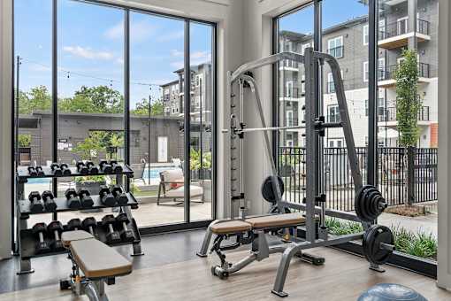 A gym with a view of apartment buildings outside the window.
