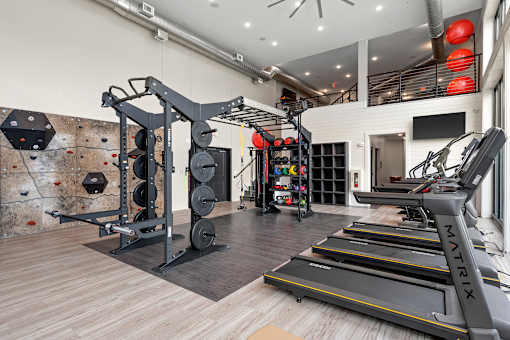 A gym with a climbing wall, treadmills, and weights.