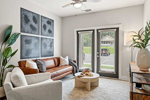 A living room with a brown couch, a white chair, a coffee table, and a ceiling fan.