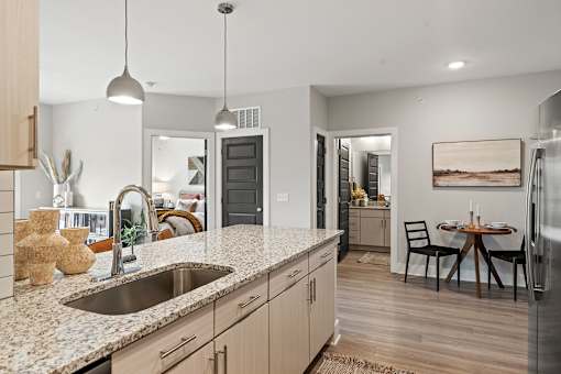 A kitchen with a granite countertop and a dining table with chairs.