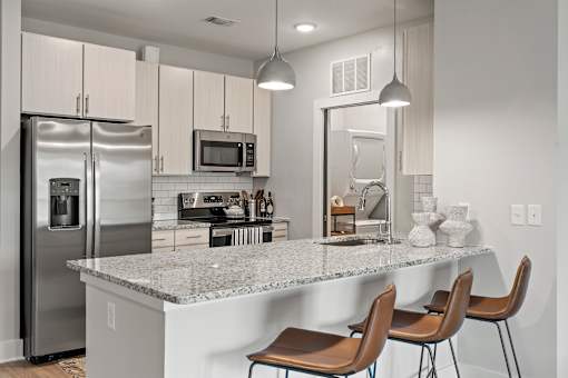A kitchen with a marble countertop and stainless steel appliances.