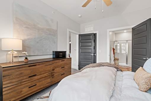 A bedroom with a bed, dresser, and a ceiling fan.