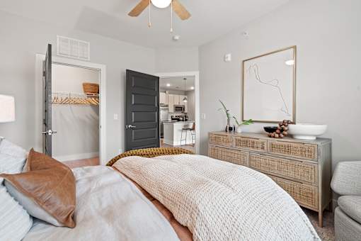 A bedroom with a large bed and a dresser with a mirror above it.