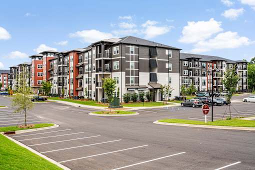 A large apartment complex with a parking lot in front.