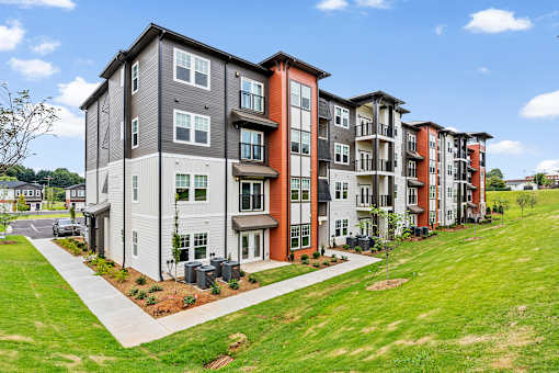 A row of modern apartment buildings with a grassy area in front.