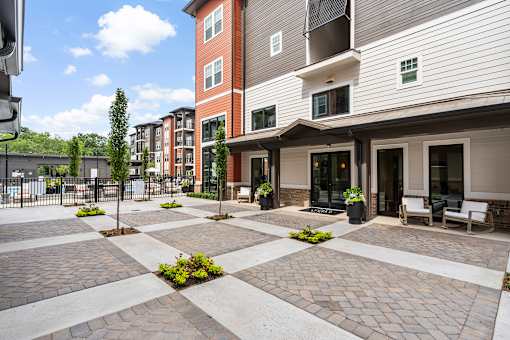 A courtyard with a brick patterned floor and a few potted plants.