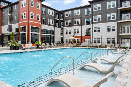 A swimming pool with lounge chairs in front of apartment buildings.