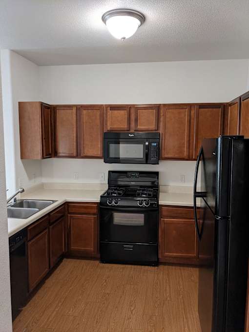 A kitchen with wooden cabinets and a black refrigerator.