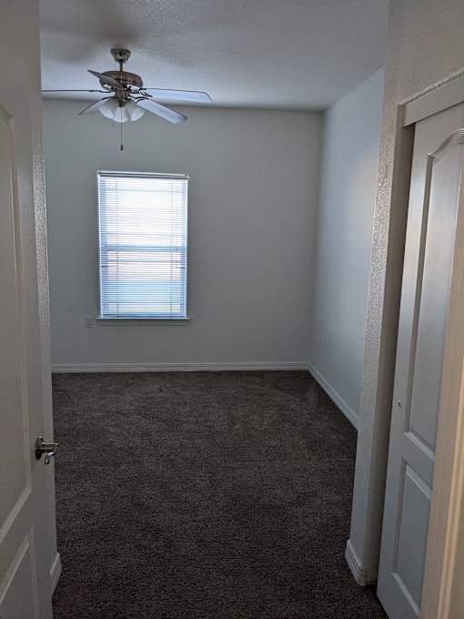 A room with a ceiling fan and a window with blinds.