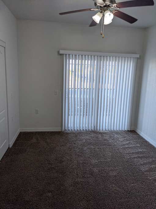 A room with a ceiling fan and carpeted floor.