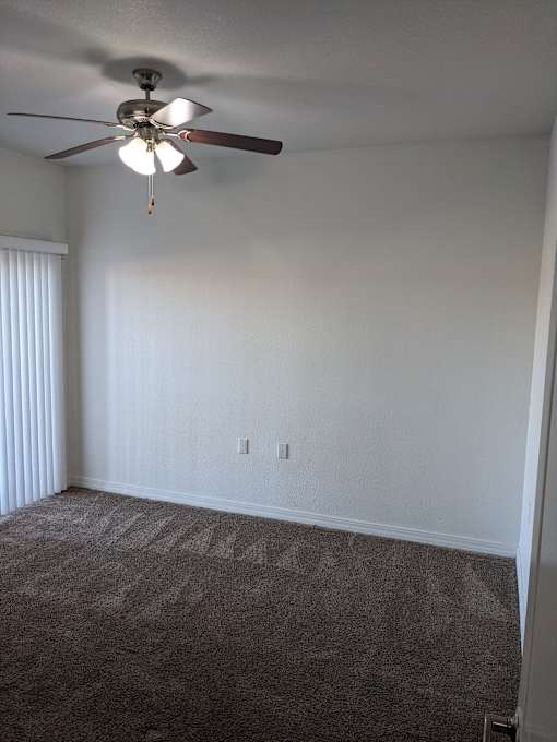 A room with a ceiling fan and carpeted floor.