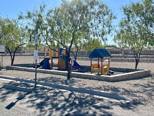 A playground with a slide and swings under a blue canopy.