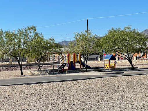A playground with a yellow slide and trees in the background.
