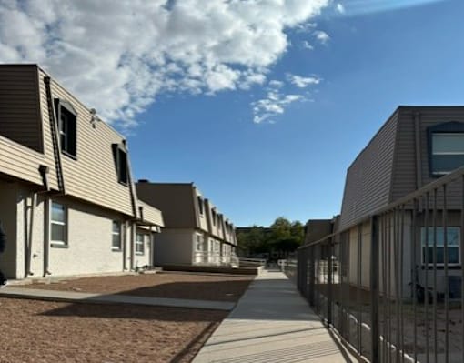 A white car is parked in front of a beige building.