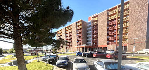 A parking lot with cars and a tall building in the background.