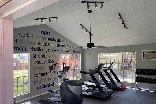 A gym with a wall of motivational words and exercise equipment.