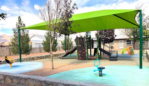 A playground with a green canopy and a slide.