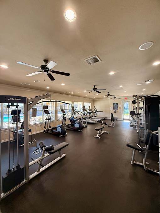 A gym with a variety of equipment including treadmills, weights, and exercise machines.