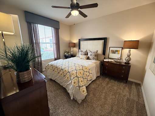 A bedroom with a bed, nightstand, and a ceiling fan.