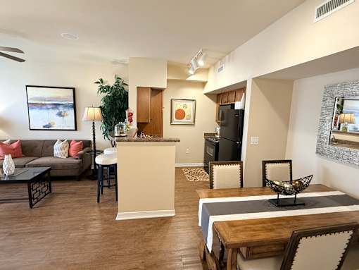 A living room with a couch, a chair, a dining table, and a potted plant.