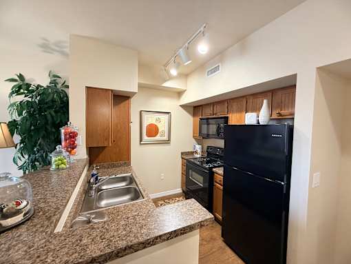 A kitchen with black appliances and granite countertops.