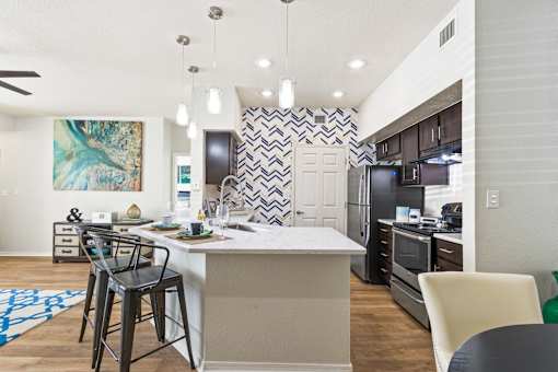 an open kitchen and dining area with bar stools in front of a kitchen island