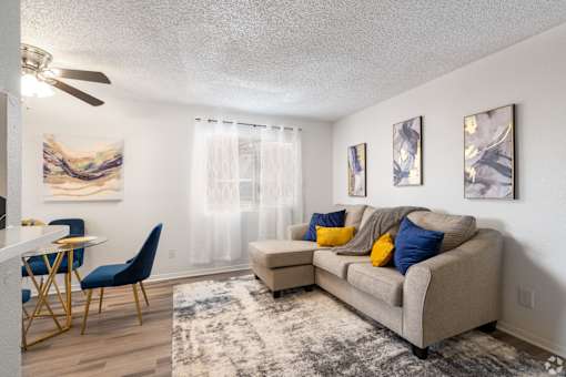 A living room with a couch, chairs, and a dining table.