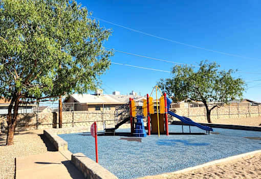 A playground with a blue water feature and a slide.