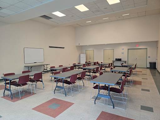 A classroom with tables and chairs and a whiteboard at the front.