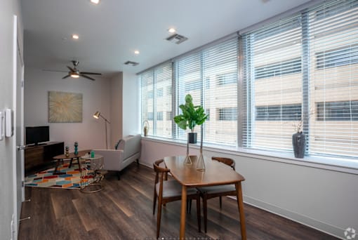 A room with a table, chairs, and a plant in a vase.