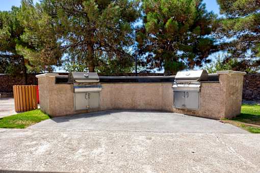two barbecue grills on the side of a driveway