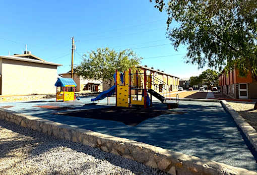 A playground with a yellow slide and a blue roofed building.