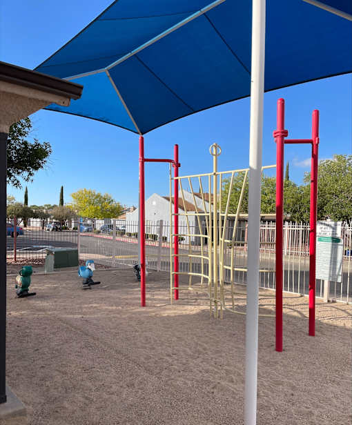 A playground with a blue canopy and red monkey bars.