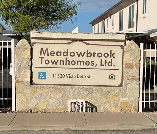 A sign for Meadowbrook Townhomes, LTD. is displayed in front of a building.