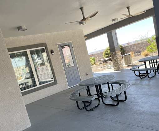 A patio with a table and chairs and a ceiling fan.