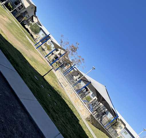 A building with a blue roof and a white wall with a tree in front of it.