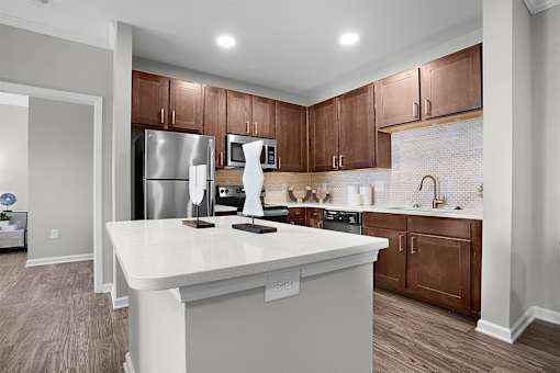 A kitchen with a white island and brown cabinets.