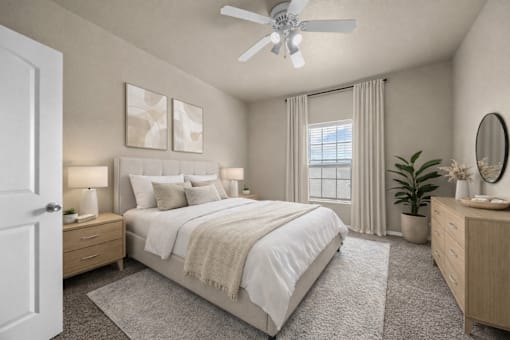 A bedroom with a large bed, a ceiling fan, and a nightstand with a lamp.