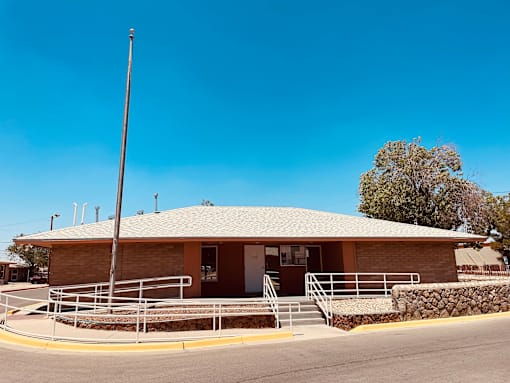 A small building with a brown roof and a stone wall in front.