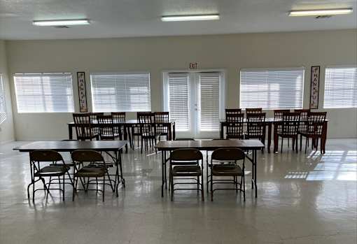 A room with tables and chairs and an exit sign.