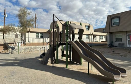 A playground with a slide and a green climbing frame.