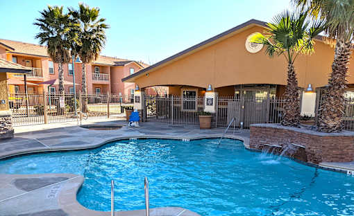 A man in a blue shirt is sitting on a bench by a pool.
