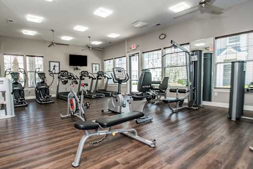 A gym with a variety of equipment including treadmills, stationary bikes, and weight machines.