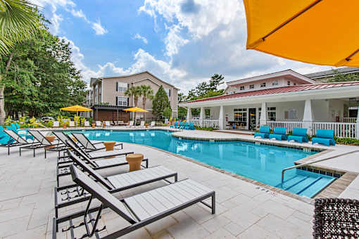 A pool area with sun loungers and a building in the background.