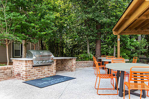 A patio with orange chairs and a grill.