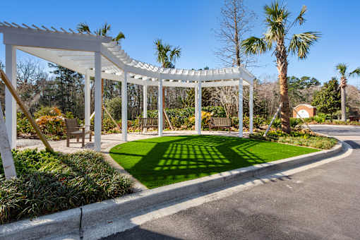 A white pergola is over a green lawn.