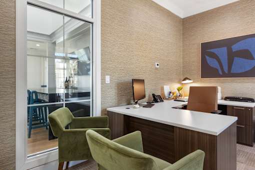 A modern office with a desk, chairs, and a painting on the wall.