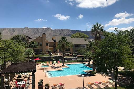 A pool surrounded by chairs and mountains in the background.