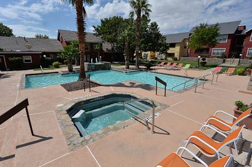 A pool area with a hot tub and lounge chairs.
